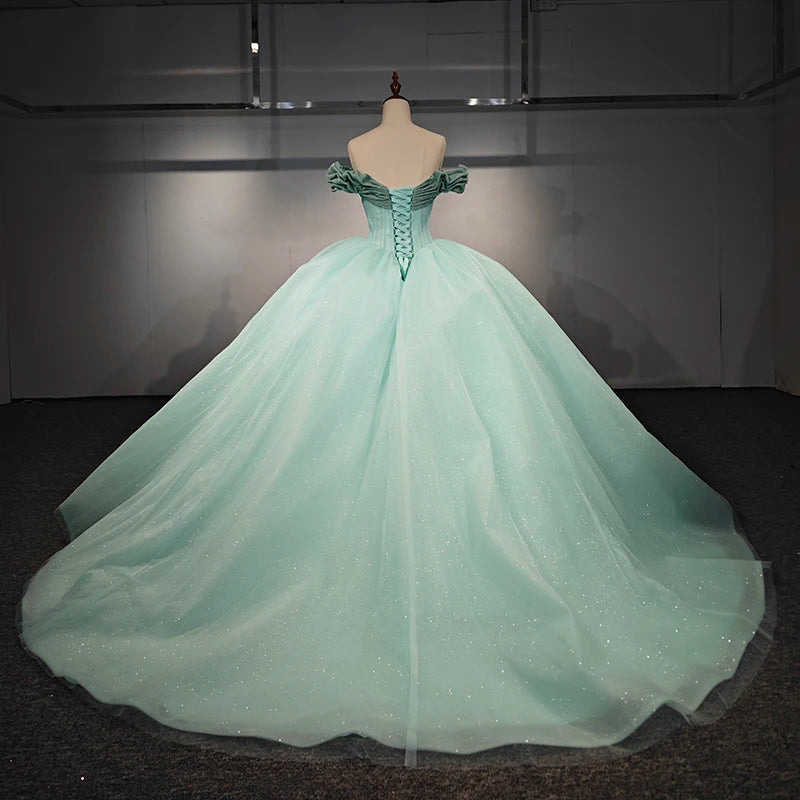 Back view of a mint green quinceanera dress with short sleeves and lace-up bodice, featuring a flowing ball gown skirt.