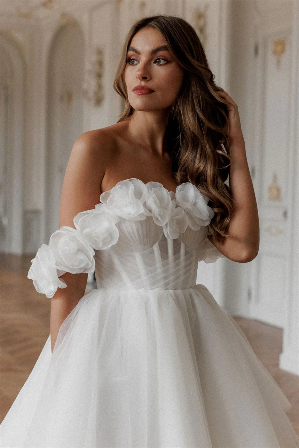 Model wearing a white mini off-the-shoulder wedding dress with floral embellishments and a corset bodice.