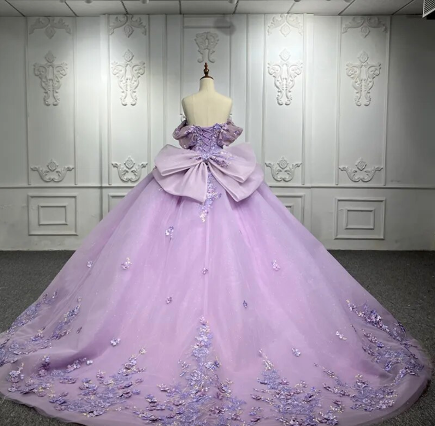 Purple Quinceanera Flower Bow Ball Gown Dress with floral embellishments and oversized bow, showcasing elegant design.