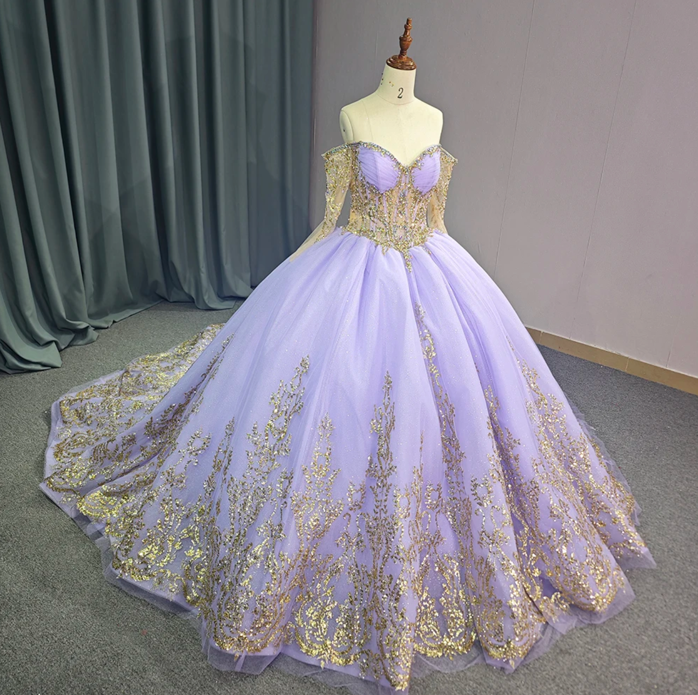 Elegant Quinceanera ball gown in purple and gold with off-the-shoulder sleeves and intricate lace details.