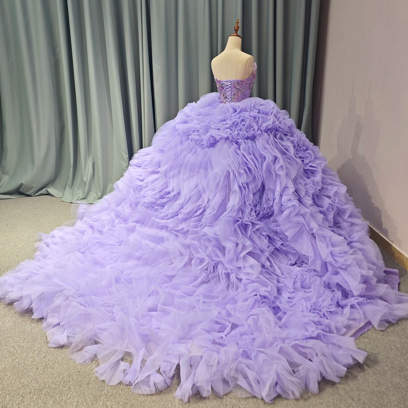 Back view of a luxurious purple quinceanera ball gown with ruffled tulle skirt and strapless design.
