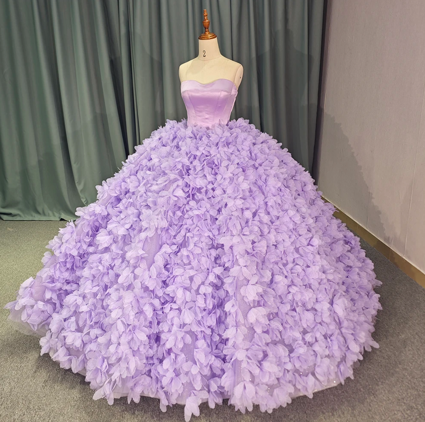 Purple strapless ball gown quinceañera dress with petal-like design and court train.