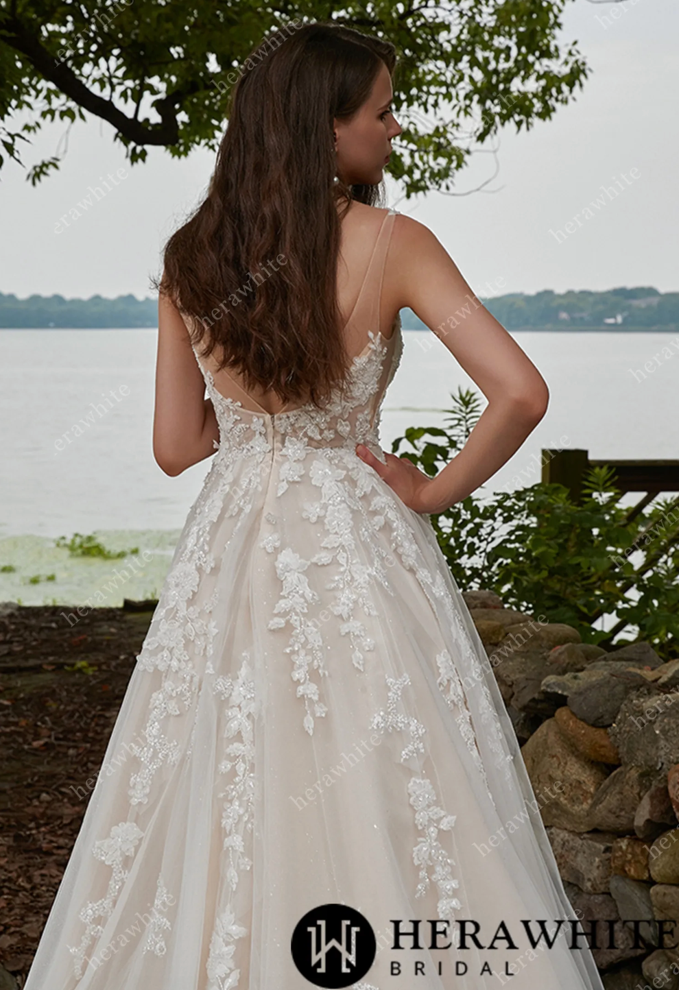 Elegant tulle wedding dress featuring floral lace appliques and a V-neck design, showcased by a model near a scenic lake.