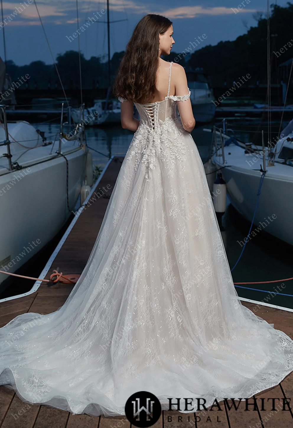 Elegant floral V-neck wedding dress with corset back and flowing train, showcased near a marina.