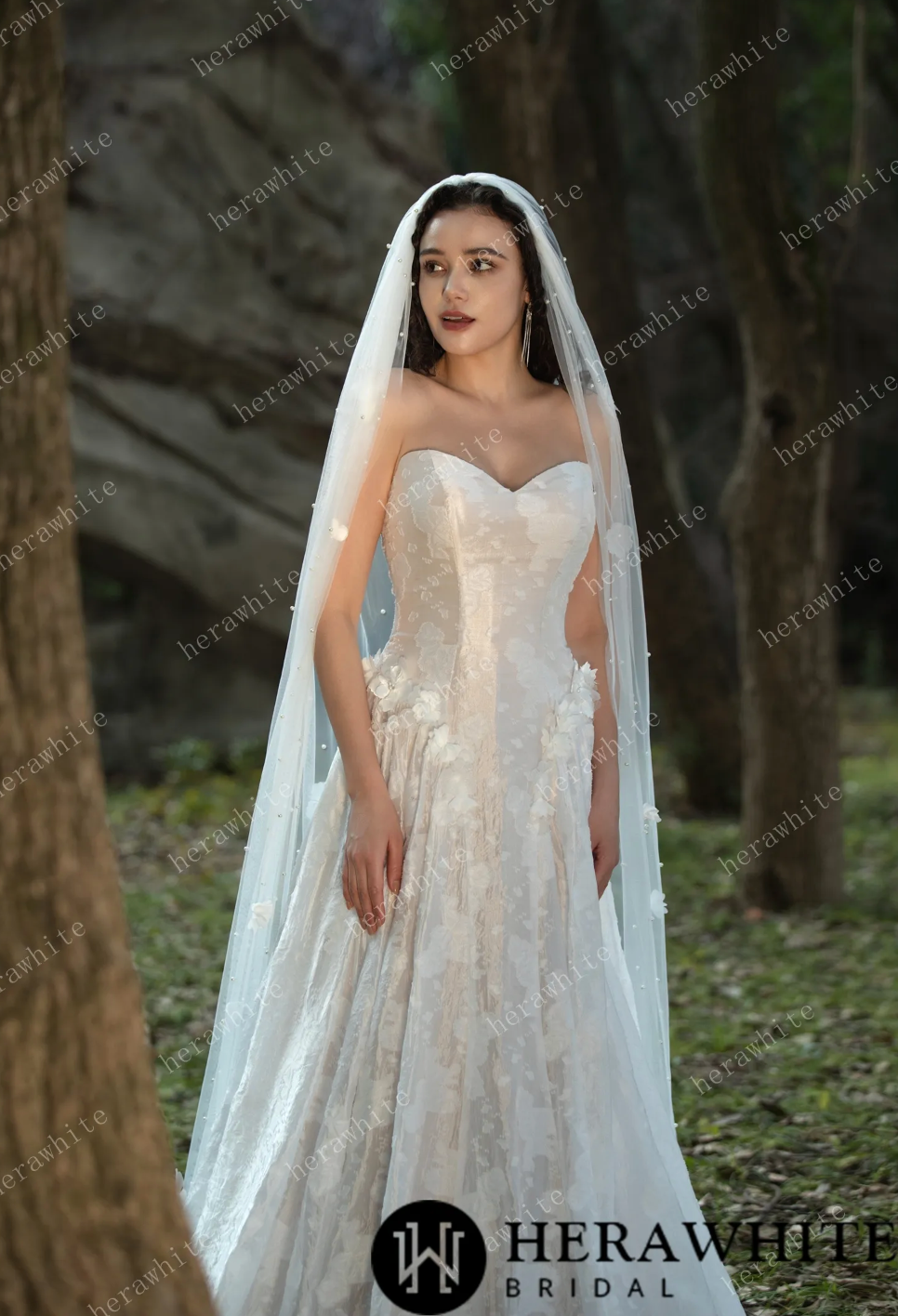 Stunning 3D flower embellished floral jacquard wedding dress with a veil, set in a serene outdoor setting.