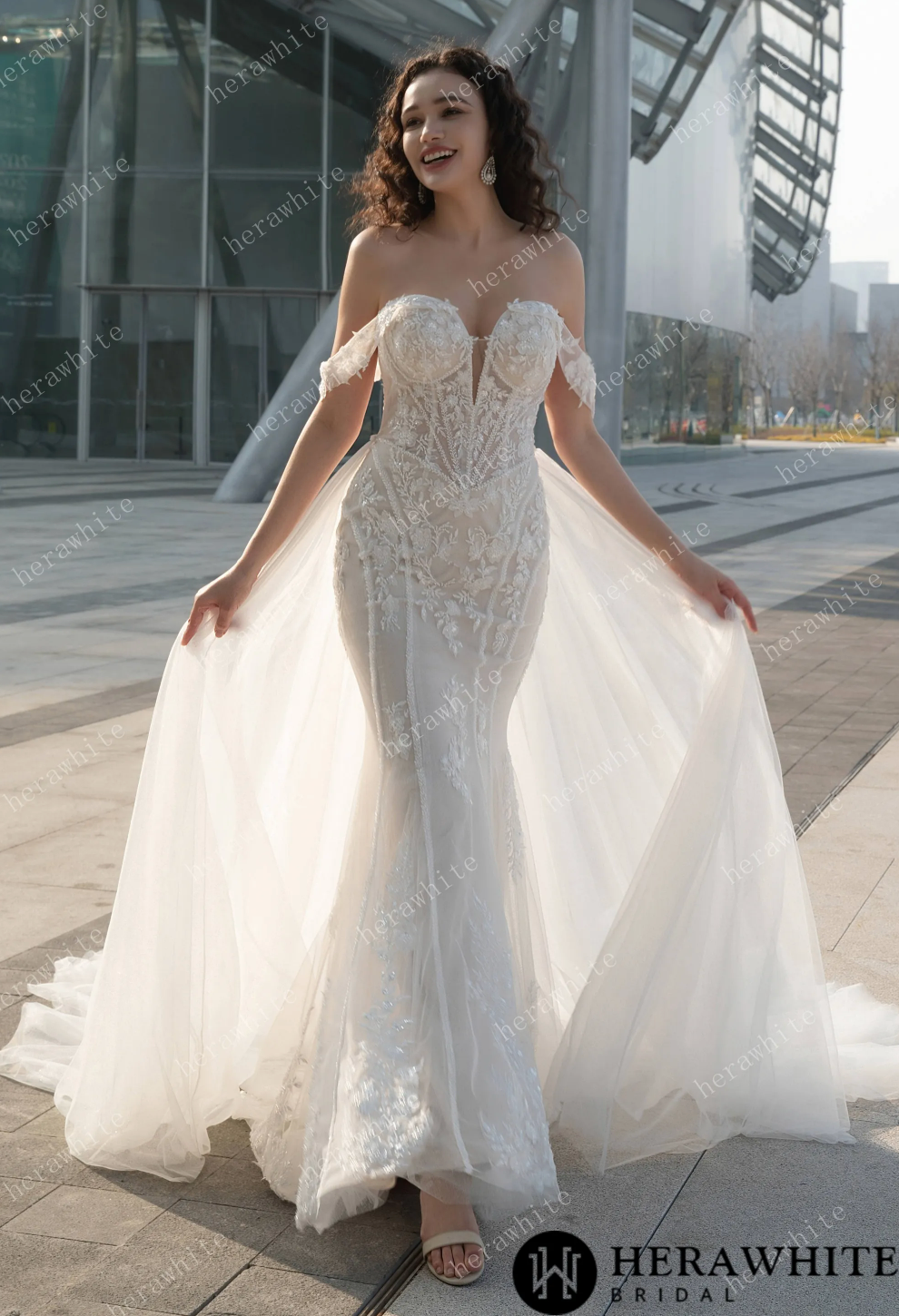 Off the shoulder wedding dress with detachable train, featuring intricate lace detail and a deep V neckline.