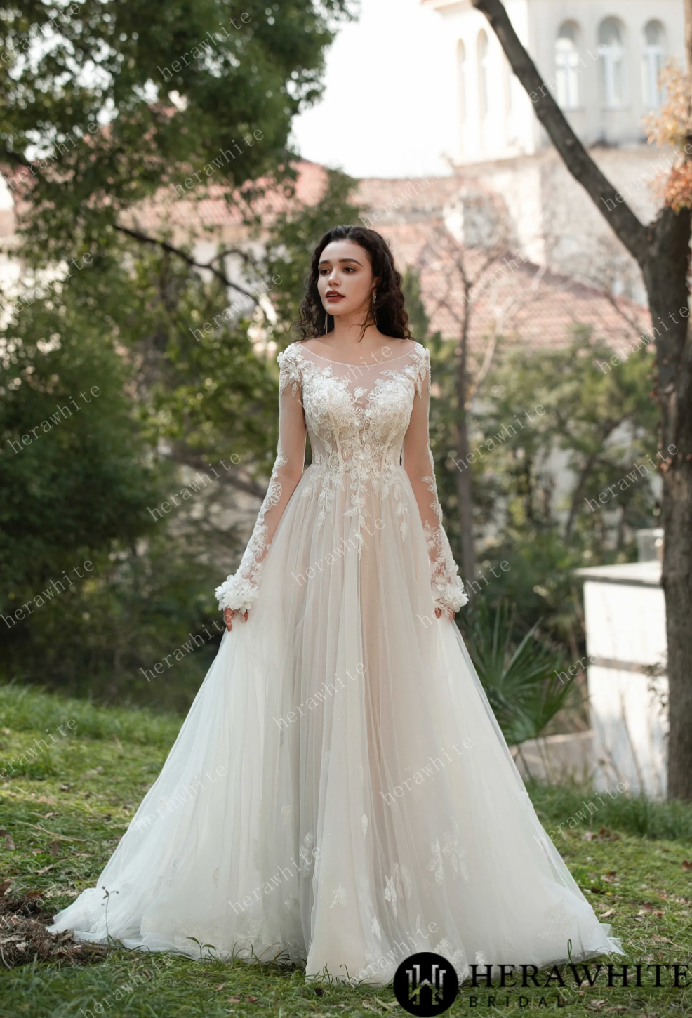 Model wearing a 3D flower bateau neckline long sleeve wedding dress in an outdoor setting.