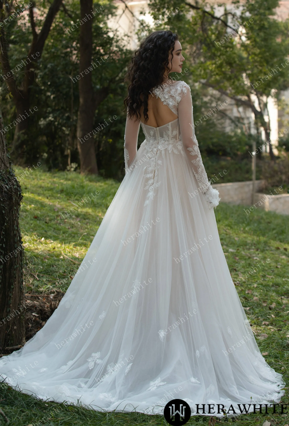 Elegant 3D flower bateau neckline long sleeve wedding dress shown from the back in a serene outdoor setting.
