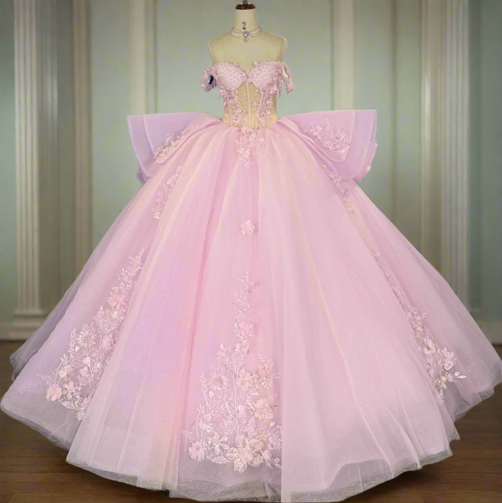 Pink evening gown with floral details on a mannequin in a room with other colorful dresses.