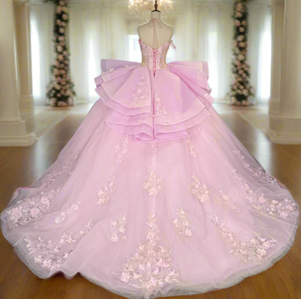 Pink evening gown with floral details on a mannequin in a room with other colorful dresses.