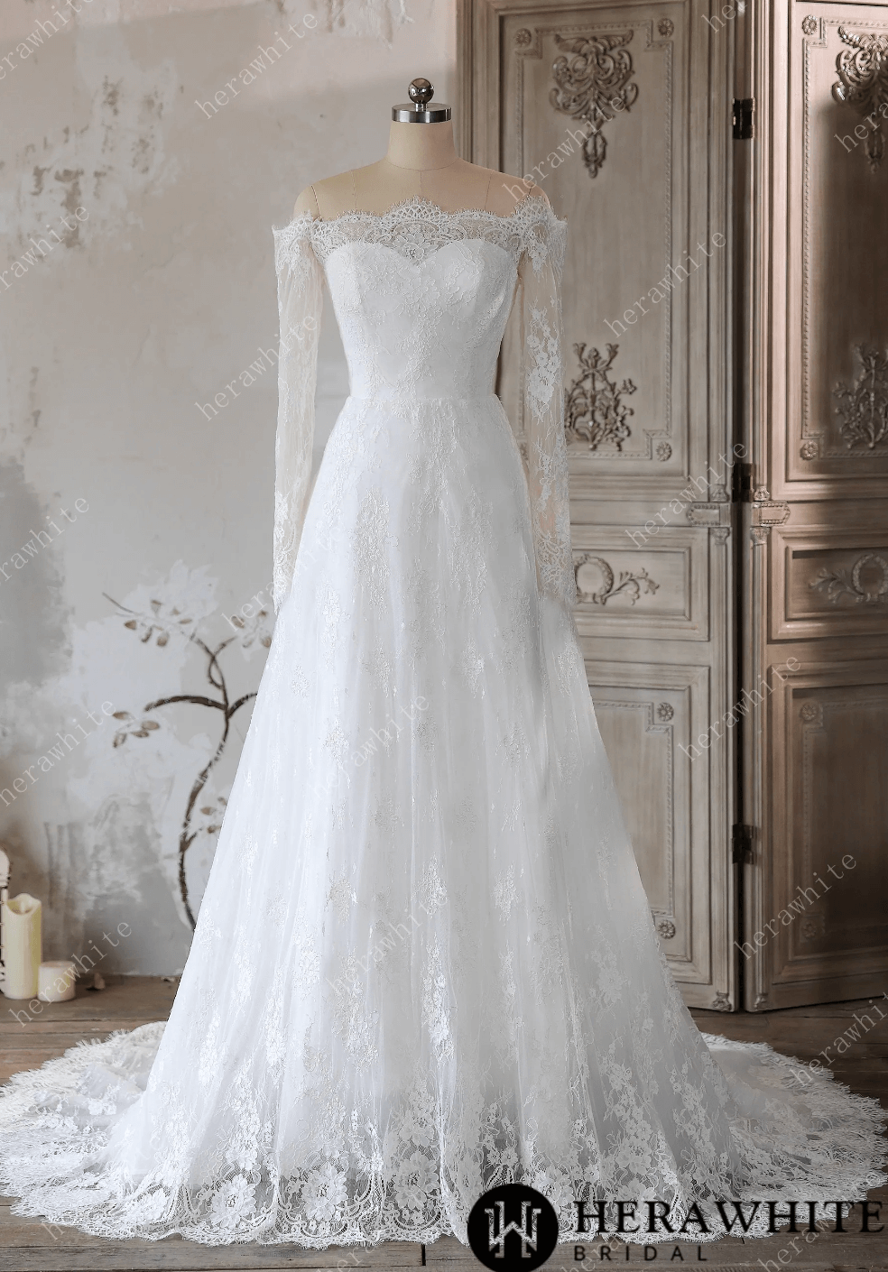 White lace wedding dress on a mannequin against a decorative wall.