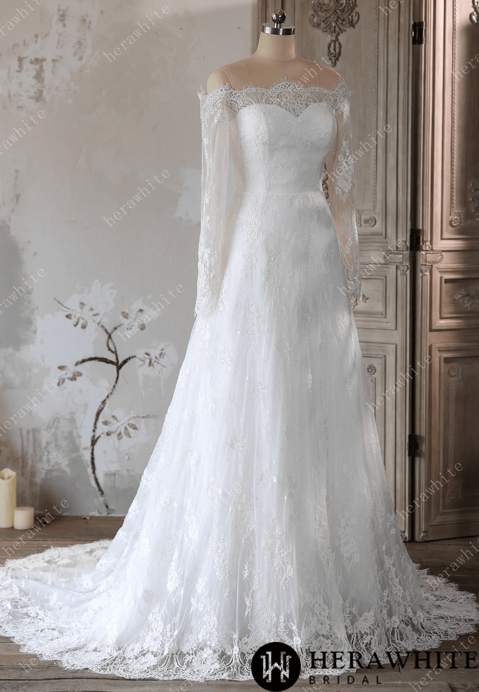 White lace wedding dress on a mannequin against a decorative wall.