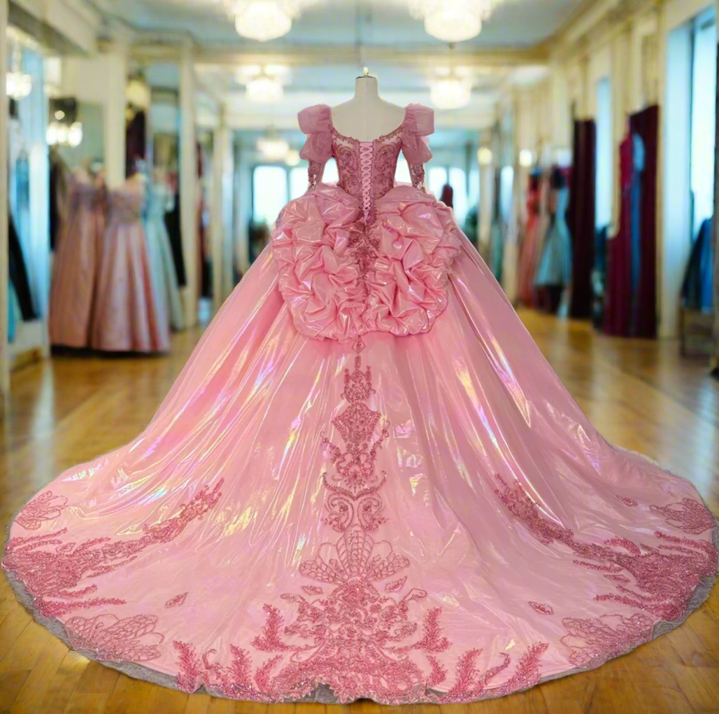 Pink evening gown with intricate detailing on a mannequin in a room with other dresses.