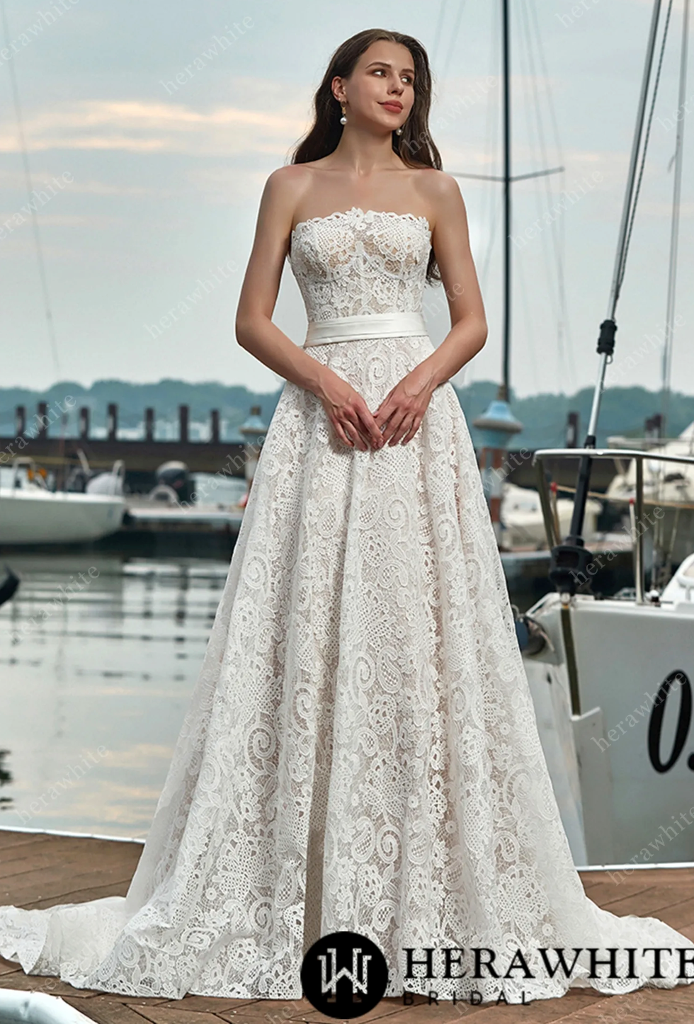 Strapless lace wedding dress with a belt and detachable bow, featuring a vintage-inspired A-line silhouette.