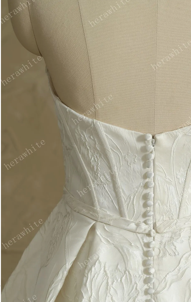 Back view of satin wedding dress showcasing detailed floral embroidery and button closure.