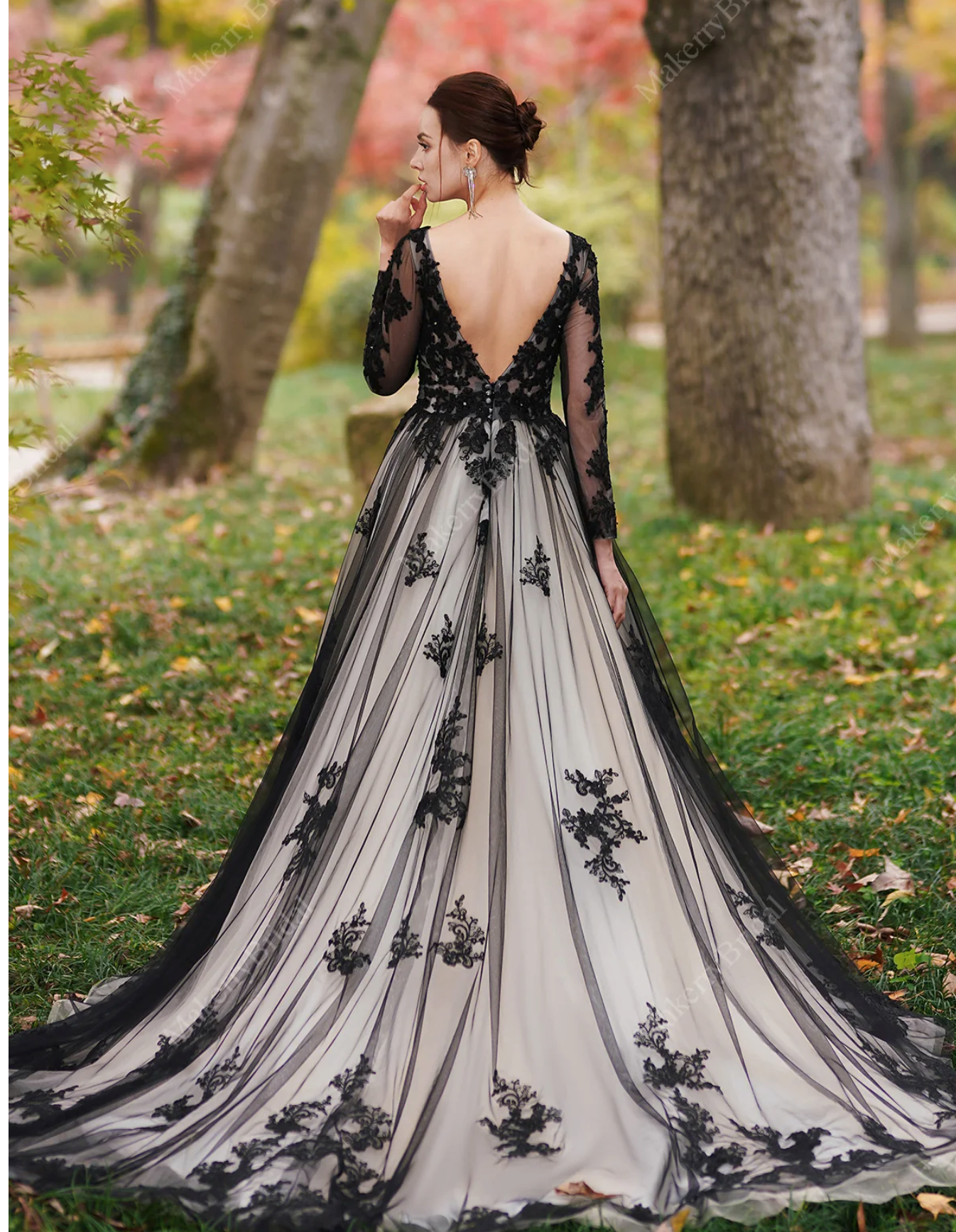 Elegant black over nude wedding dress with beaded lace, featuring a plunging V-back and long sleeves, set in a natural outdoor setting.